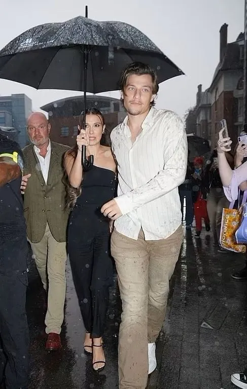 A Sectech officer beside two clients sharing an umbrella in the rain
