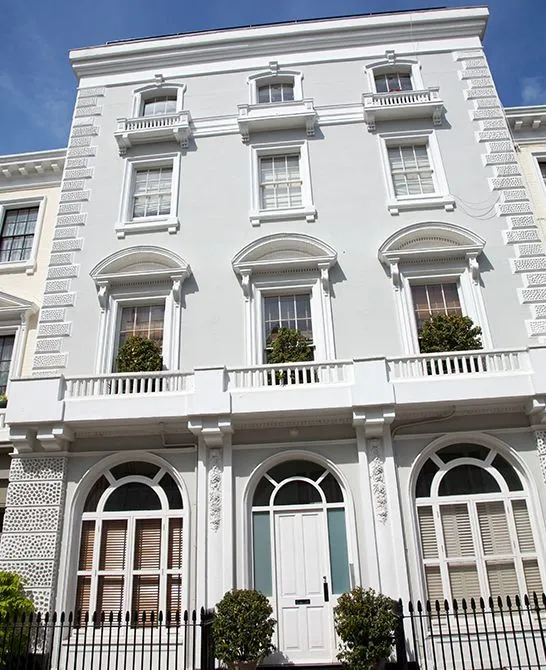 The front elevation of a white stuccoed London townhouse behind iron railings