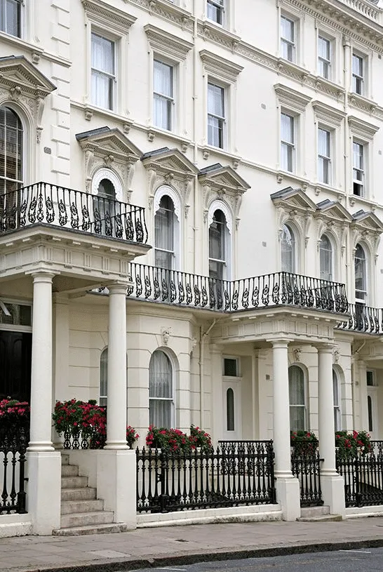 A row of white stuccoed London townhouses with columned porches and iron railings
